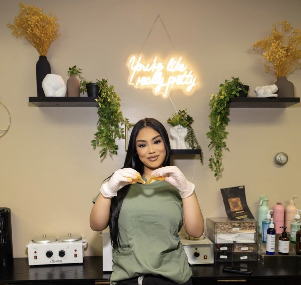 India, the esthetician and owner of Soleil Beauty Bar, holding sugar paste in her Hartford studio beneath a neon sign reading You're like really pretty